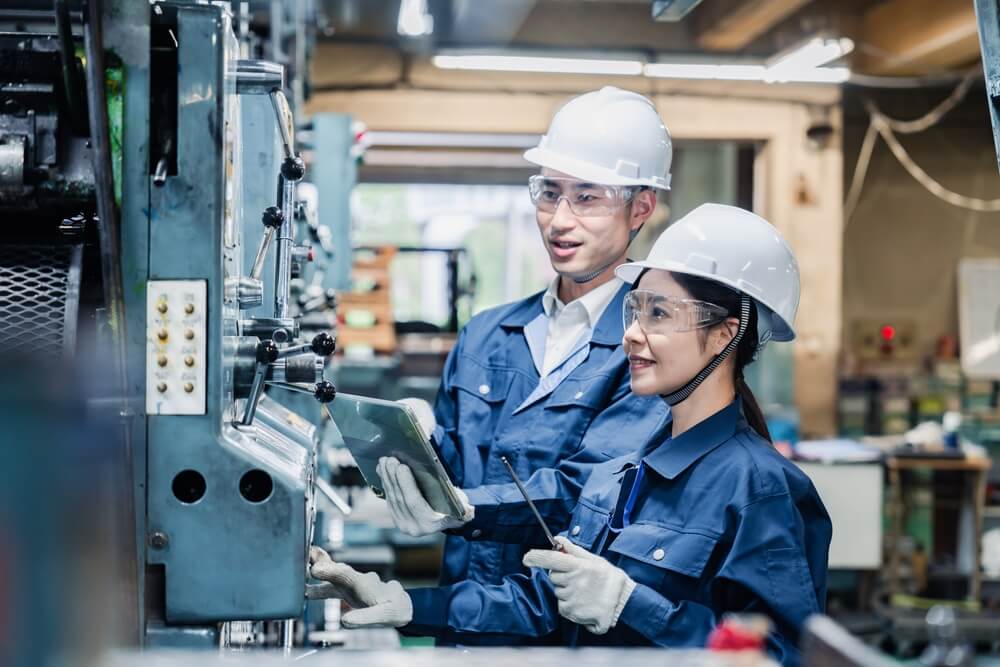 Chinese workers manufacturing a product together in a factory.