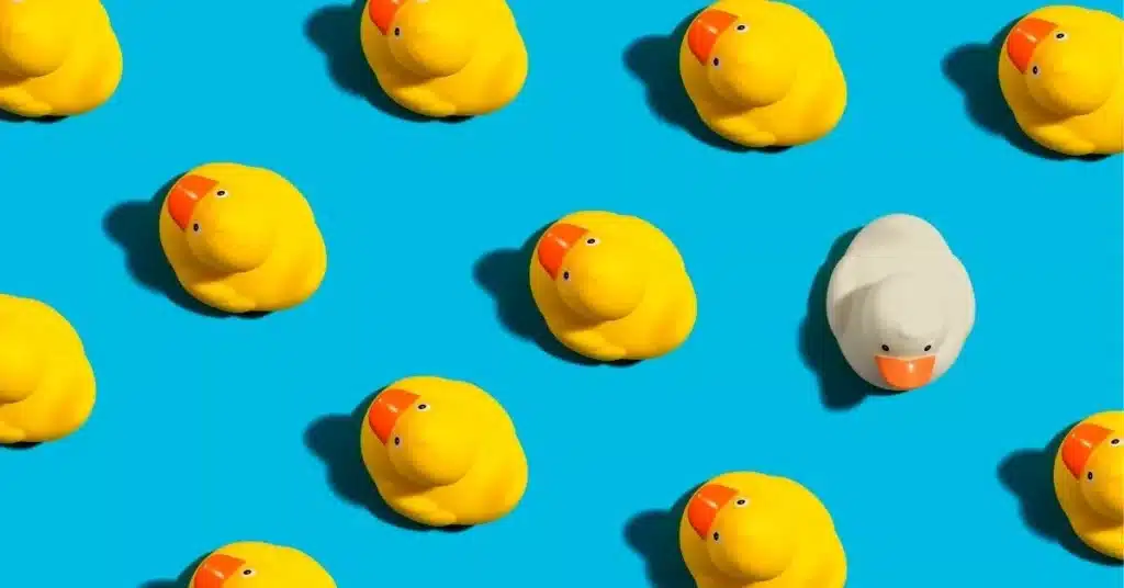 Yellow toy ducks with one white duck standing out, symbolizing unique product development and product innovation.